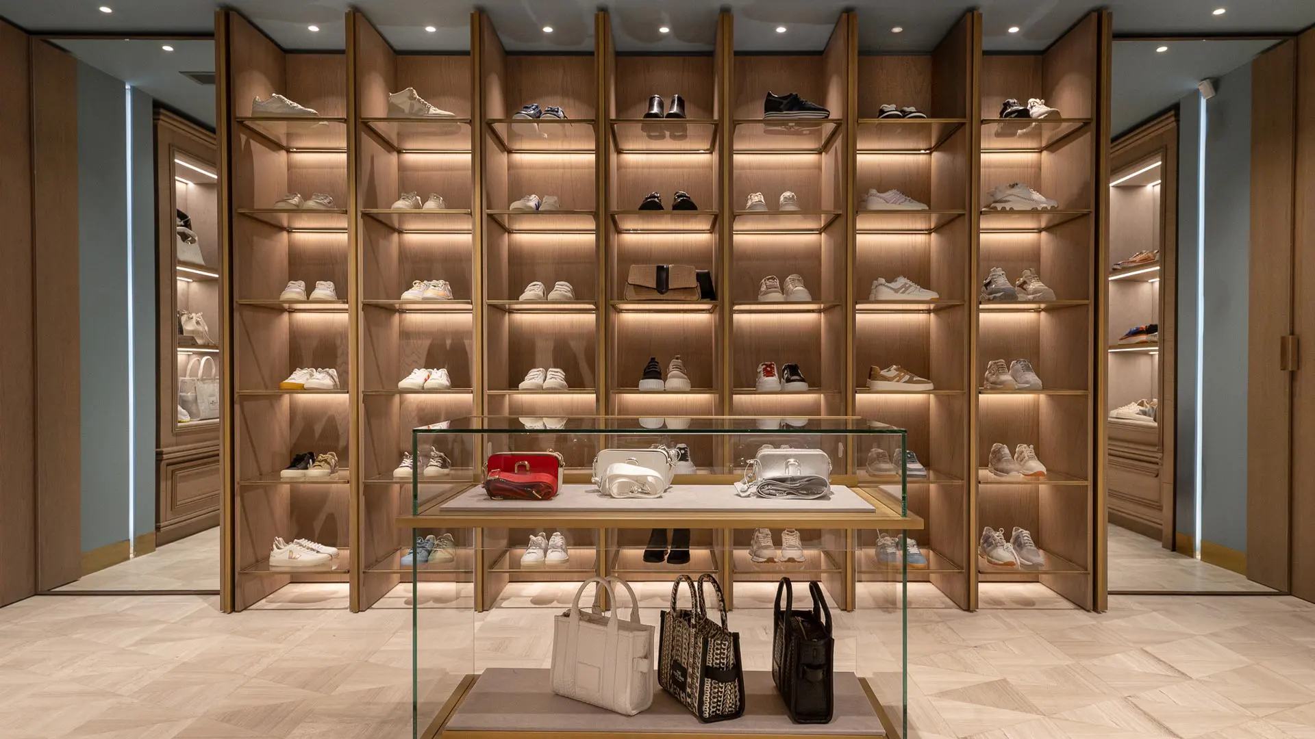Χώρος καταστήματος με ξύλινα ράφια, φωτιζόμενες βιτρίνες και έκθεση παπουτσιών και τσαντών